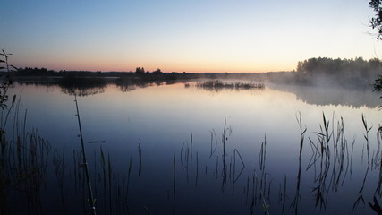 Morning dawn of the sun through the mist over the water. Early morning in the forest on the river.