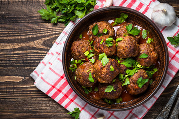 Meatballs in tomato sauce on wooden table top view.