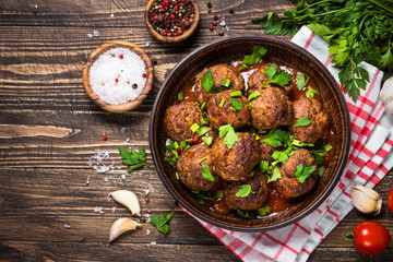 Meatballs in tomato sauce on wooden table top view.