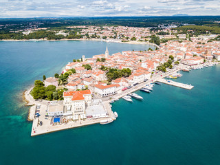 Croatian town of Porec, shore of blue azure turquoise Adriatic Sea, Istrian peninsula, Croatia. Bell tower, red tiled roofs of historical buildings, boat, piers. Euphrasian Basilica. Aerial view
