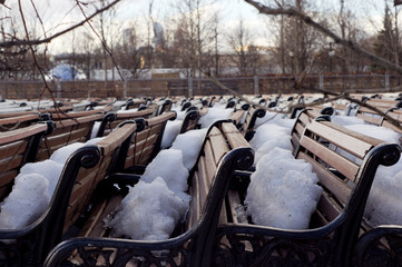 Park benches stored and covered with show in early spring