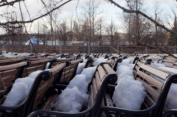 Park benches stored and covered with show in early spring