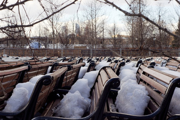 Park benches stored and covered with show in early spring