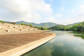 Fototapeta premium Wooden floor platform and lake with green mountains background in Hangzhou