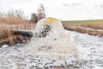 schmutziges Wasser fließt aus einem Abflussrohr in den Fluss und belastet die Umwelt