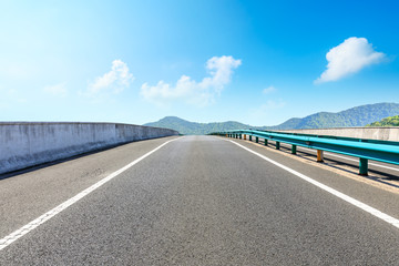 Empty asphalt road and mountains with blue sky on a sunny day