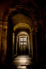 A gloomy corridor with a door at the end, from which comes the light