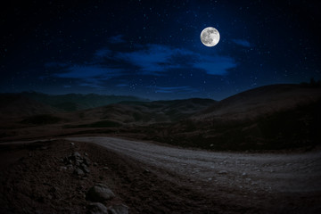 Naklejka na ściany i meble Mountain Road through the forest on a full moon night. Scenic night landscape of country road at night with large moon. Long shutter photo