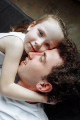 Fototapeta premium Dad with his daughter lie on a black sheet. Happy family life. View from the top.