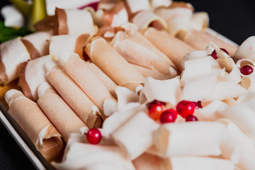 Luncheon meat. Different kind of meat, ham and bacon sliced and served with horseradish, cranberries and pickes on a white plate