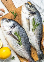 Raw dorado fish on cutting board on the table.