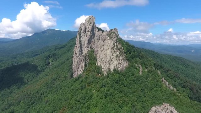 A large rock outcrops against the blue cloudy sky.