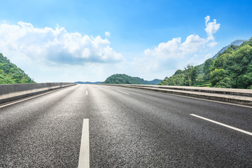 Empty asphalt road and mountains with blue sky on a sunny day