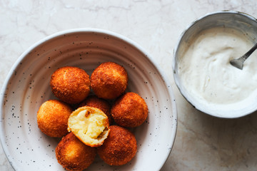 hot fried golden potato croquettes with mozzarella cheese in a bowl with yogurt sauce top view space for text