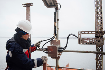 A woman in overalls, protective helmet and goggles working