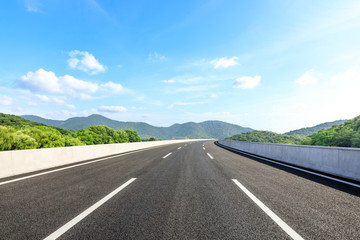 Empty asphalt road and mountains with blue sky on a sunny day
