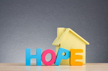 House or real estate concept, HOPE word made from wooden letter on desk over gently lit dark background - 261703320
