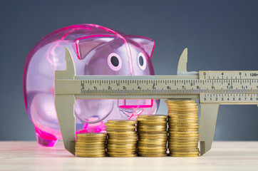 financial crisis and saving money concept,vernier caliper and stacking coins on wooden desk over...