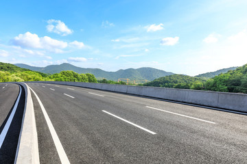 Fototapeta premium Empty asphalt road and mountains with blue sky on a sunny day