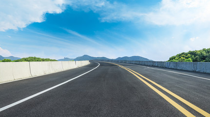 Fototapeta premium Empty asphalt road and mountains with blue sky on a sunny day