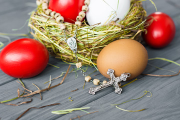 Easter background with dark red Easter eggs in nest and catholic rosary with a cross. Top view with copy space. 