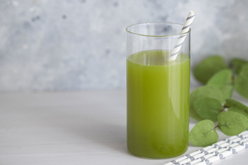 Freshly blended green smoothie in in a glass with straws on the table. Detox vegetable juice....