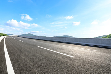 Empty asphalt road and mountains with blue sky on a sunny day