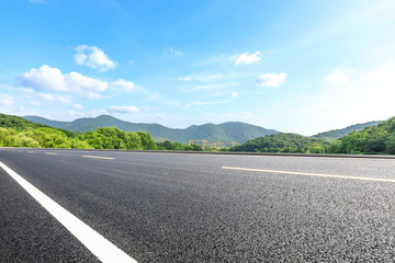 Empty asphalt road and mountains with blue sky on a sunny day