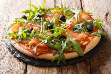 Recipe for delicious Italian pizza with salmon, arugula, black olives and mozzarella cheese close-up. horizontal