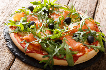 Gourmet Italian pizza with salmon, arugula, black olives and mozzarella cheese close-up. horizontal