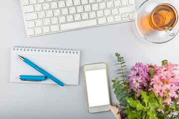 White office desk table with keyboard, phone, writing supplies and flowers, stylish office , top view