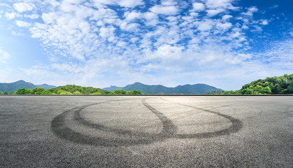 Fototapeta premium Asphalt race track ground and mountains with blue sky landscape