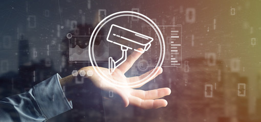 Businessman holding Security camera system icon and statistics data - 3d rendering