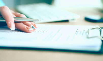 Hand of businesswoman filling and signing with silver pen partnership agreement form clipped to pad close-up. Management training course, some important document, team leader ambition concept