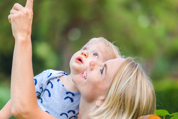 Naklejka premium Mom shows something in the sky to her little baby boy