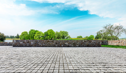 Rough square stone floor and green woods with sky background