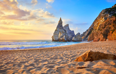 Portugal Ursa Beach at atlantic coast of Atlantic Ocean with rocks and sunset sun waves and foam at sand of coastline picturesque landscape panorama.