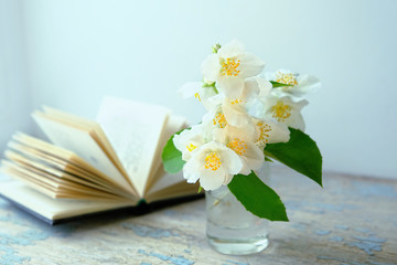 Jasmine flowers and book. beautiful artistic image of spring season. romantic scene with book and white Jasmine flowers. composition with spring flower. soft focus, close up.
