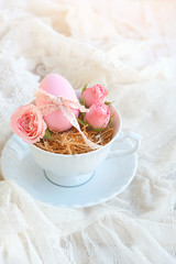 beautiful Easter still life with easter eggs. colored eggs and rose flowers in Cup on wooden background. happy Easter holiday concept.