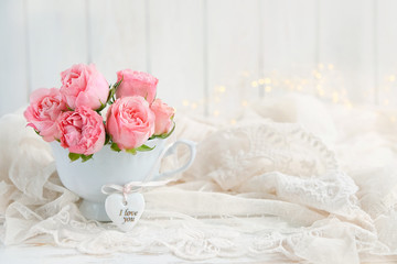 Obraz na płótnie Canvas flowers roses in Cup and heart on white background. beautiful still life. beautiful scene of love and tenderness, background greeting with Valentine's day, birthday