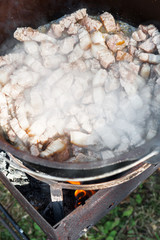 Meat is cooking in the pot, meat on the fire for rice pilau outdoors. Camping in the nature and preparing food conceptMeat is cooking in the pot, meat on the fire for rice pilau outdoors. Camping in t