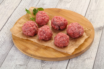 Raw meatball over wooden background