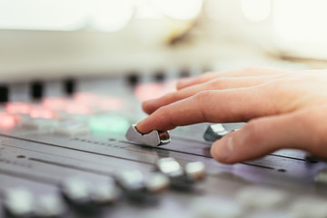 Radio broadcasting studio: Moderator is using the soundboard, computer in the background