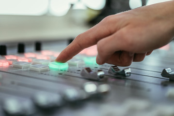 Radio broadcasting studio: Moderator is using the soundboard, computer in the background