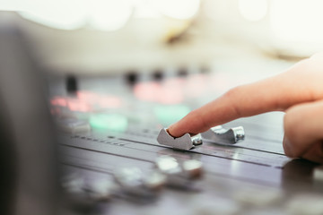 Radio broadcasting studio: Moderator is using the soundboard, computer in the background