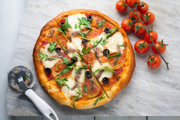 Pizza con mozzarella, pomodoro, acciughe, rucola e olive nere