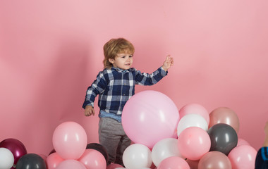 Fototapeta na wymiar Child plays balloons. Caucasian baby boy plays with baloons at home. Adorable little boy with pink baloon on pink background