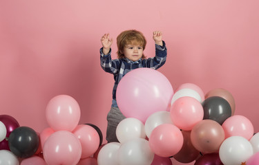 Fototapeta na wymiar Pink, white and gray balloons for celebration. Funny kid play on his own on pink background. Cute boy wearing blue shirt. Clothes for children