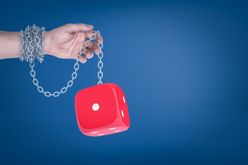 Fototapeta na wymiar Male hand chained to red dice on blue background
