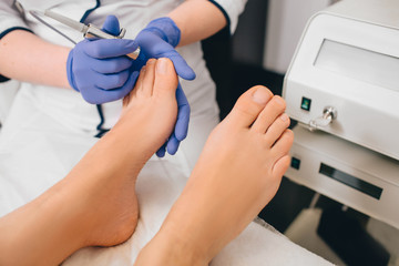 Patient receiving laser treatment on toenail, close-up. Fungal infection on the toenails. Onychomycosis treatment at clinic with medical laser